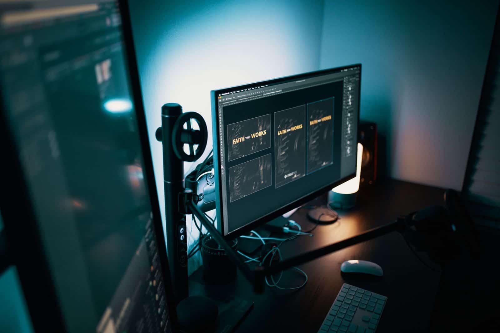 Dual monitors on a designer's desk showing a website layout under soft studio lighting