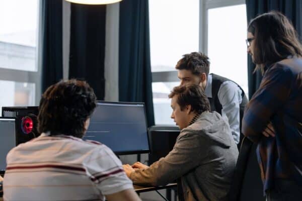 Web development team collaborating over source code on a monitor in a modern agency studio