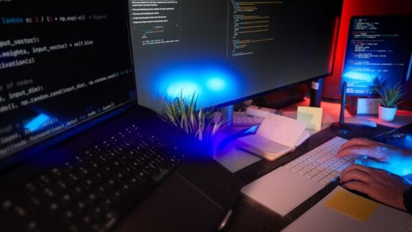 A single developer coding on a laptop and monitors displaying source code at a focused desk setup